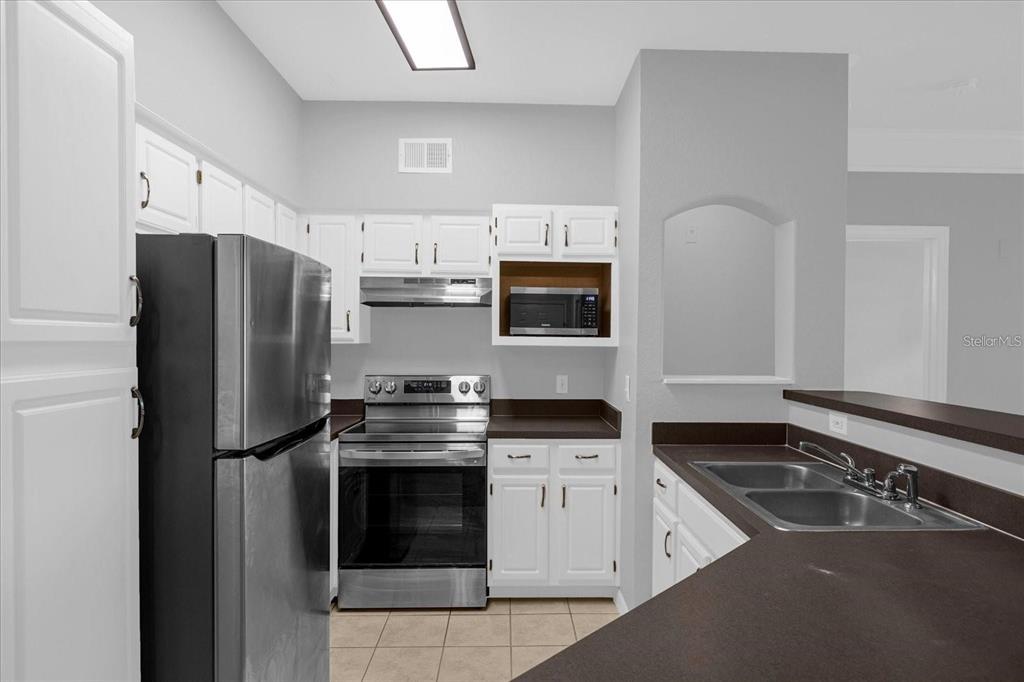 3250 Corona Village Way, Unit 102 Orlando, FL 32835 - Photo 8 of 33 a kitchen with stainless steel appliances a stove a sink and a refrigerator