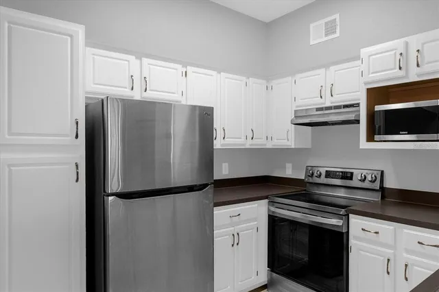 a kitchen with stainless steel appliances a refrigerator sink and microwave