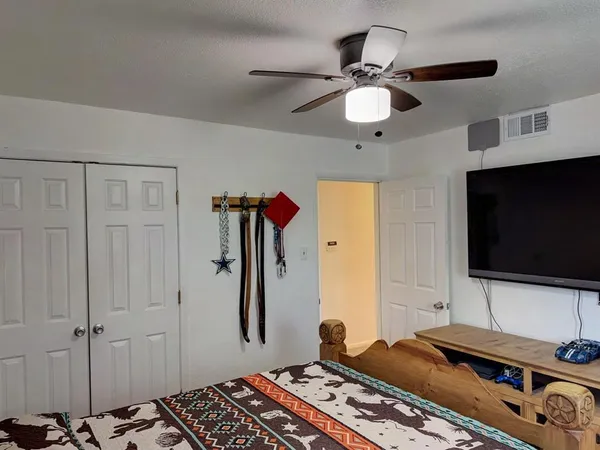 a bedroom with a bed and a flat tv screen on the dresser