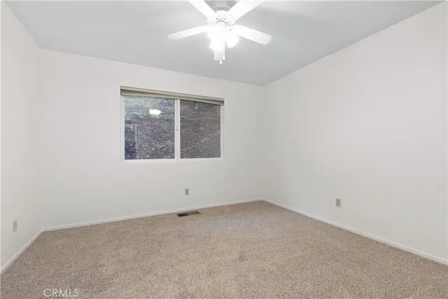 an empty room with a window and a fan