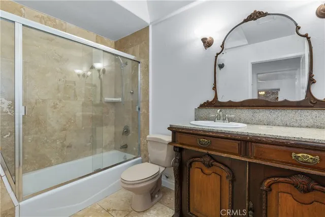 a bathroom with a granite countertop toilet sink and mirror
