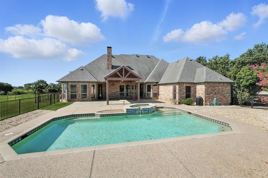View of pool with a patio, a fenced backyard, and a pool with connected hot tub