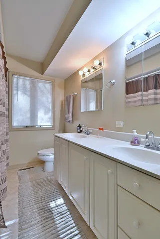 a spacious bathroom with a double vanity sink toilet and a window
