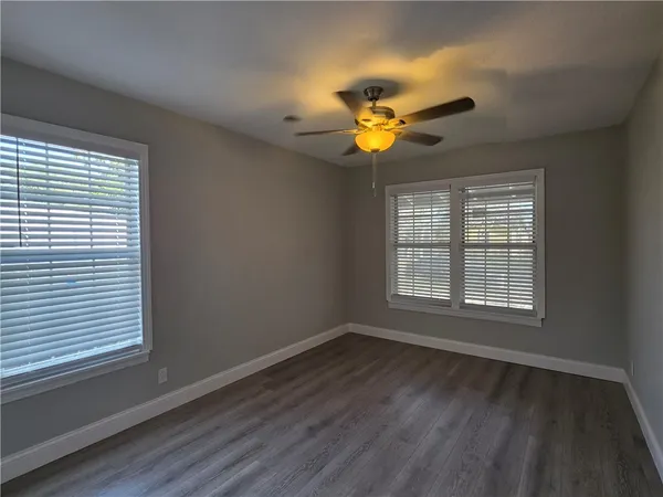 an empty room with wooden floor and a ceiling fan