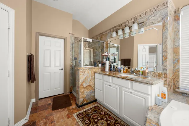 a large white kitchen with a sink a refrigerator and a granite counter tops