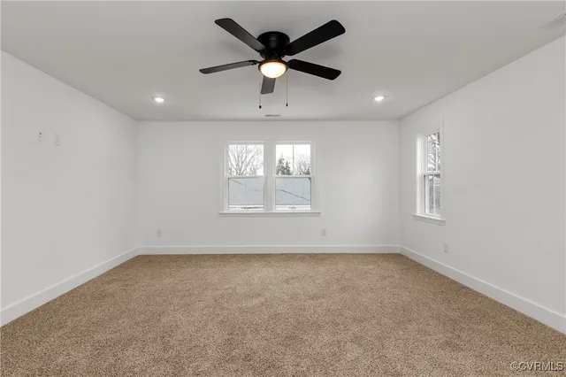 an empty room with a ceiling fan and window