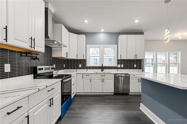 a kitchen with white cabinets stainless steel appliances a sink and a window