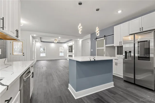 a large kitchen with stainless steel appliances kitchen island a large counter top and wooden floors