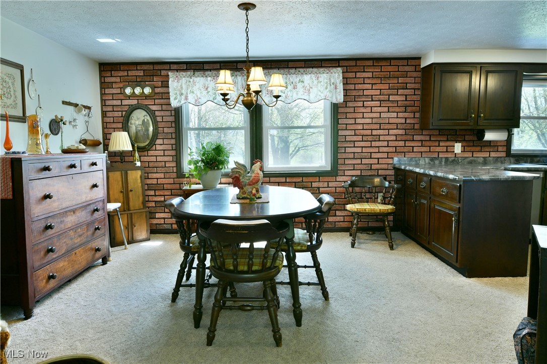 379 Housel Craft Road Bristolville, OH 44402 - Photo 17 of 50 Dining space featuring a notable chandelier, a textured ceiling, and light colored carpet