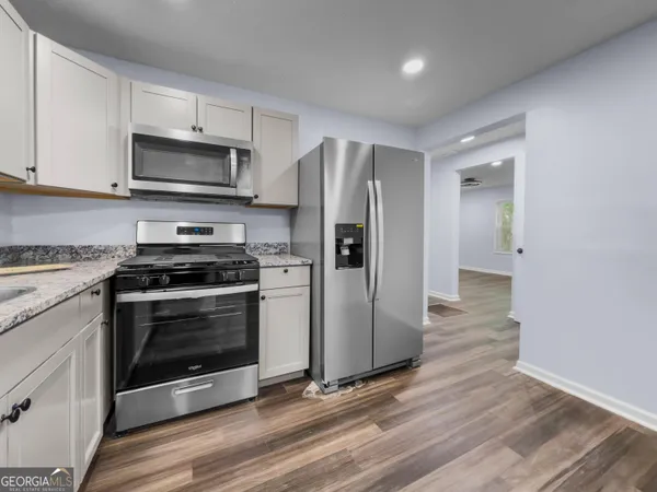 a kitchen with stainless steel appliances a stove a microwave and a hard wood floors