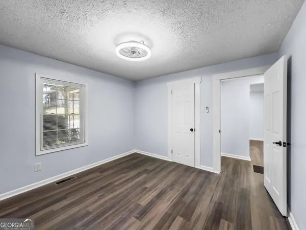 an empty room with wooden floor and windows