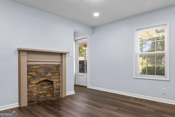 an empty room with wooden floor closet and windows