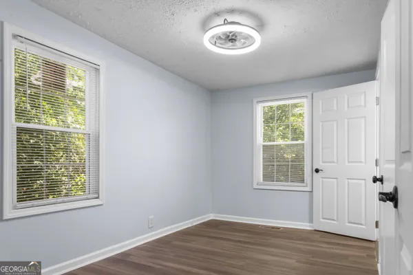 a view of an empty room with a window and wooden floor