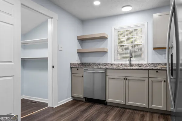 a kitchen with granite countertop cabinets stainless steel appliances a sink and a window
