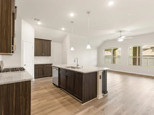 a kitchen with stainless steel appliances granite countertop a sink a stove and a wooden floors