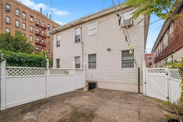 a view of a white house with a large tree and wooden fence