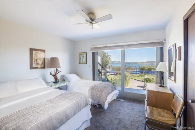 a bedroom with two beds and a large window with balcony view