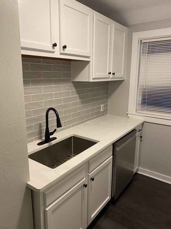 a kitchen with granite countertop white cabinets and a sink