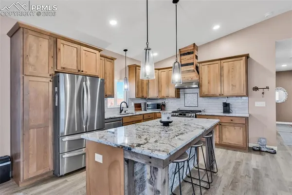 a kitchen with stainless steel appliances granite countertop a refrigerator a sink and a stove