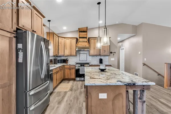 a kitchen with a refrigerator a sink and wooden floor