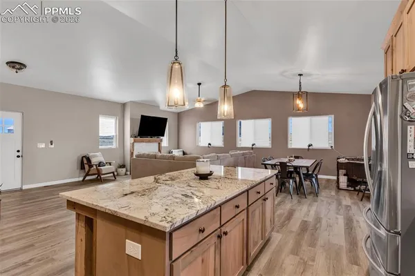 a kitchen with granite countertop kitchen island stainless steel appliances a sink stove and wooden floor