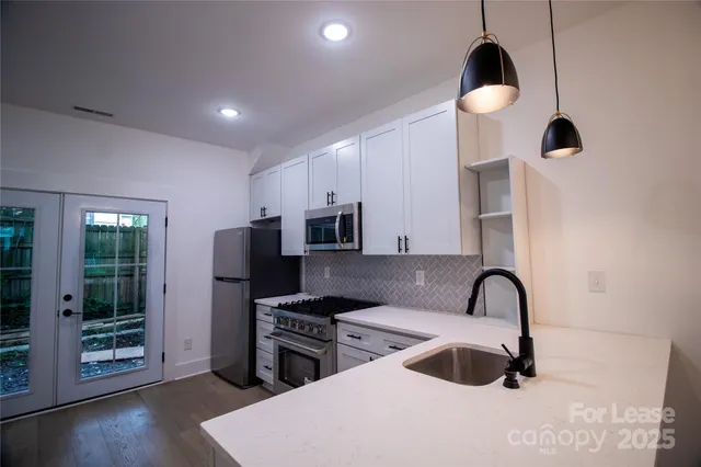 a kitchen with stainless steel appliances a stove a sink a refrigerator and wooden floor