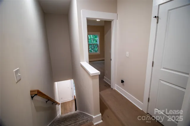 a view of a hallway with wooden floor and staircase