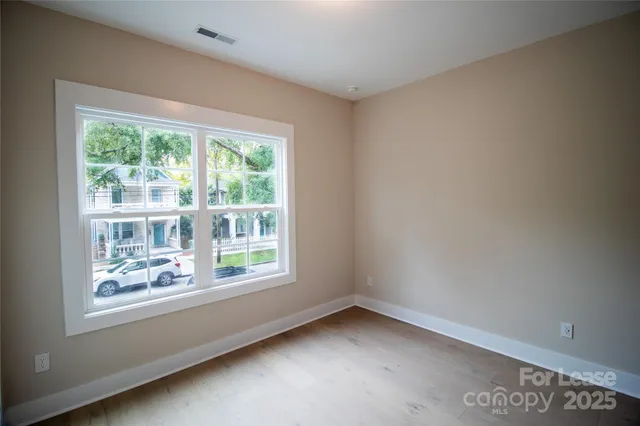 a view of a big room with wooden floor and windows