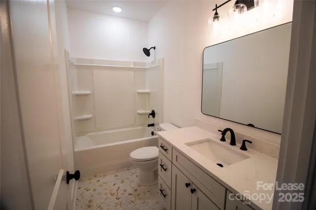 a bathroom with a bathtub shower sink vanity mirror and toilet