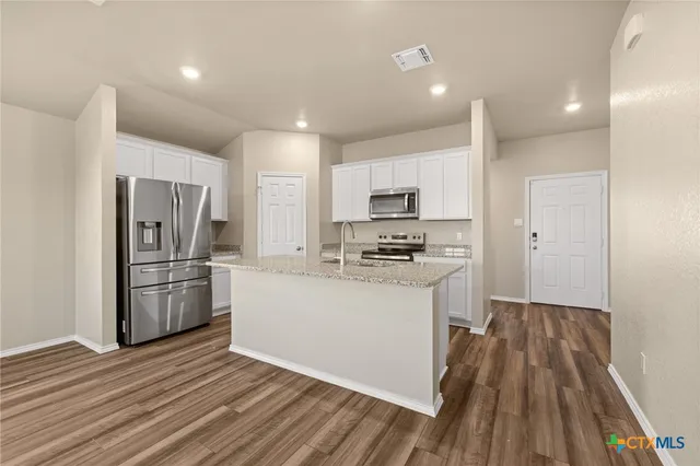 a kitchen with a refrigerator a stove top oven and wooden floor