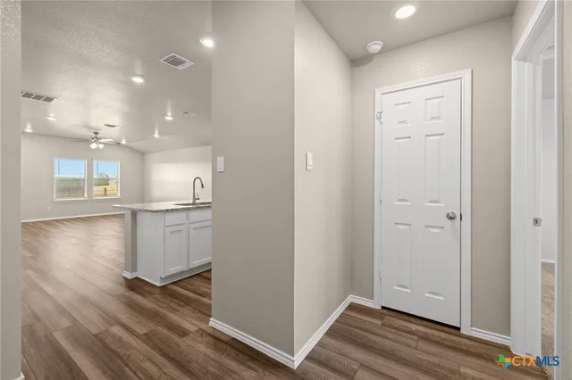 a view of kitchen and empty room with wooden floor