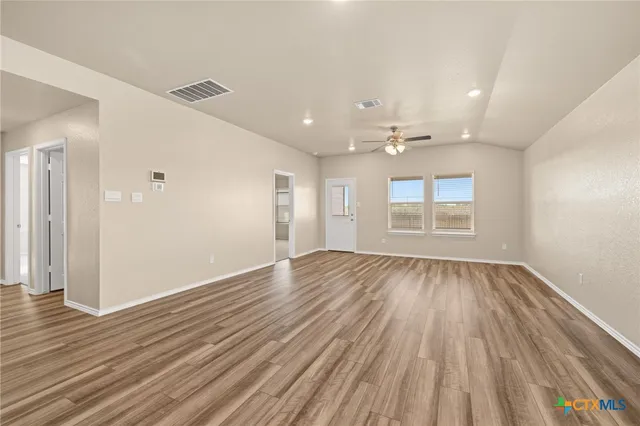 an empty room with wooden floor and windows