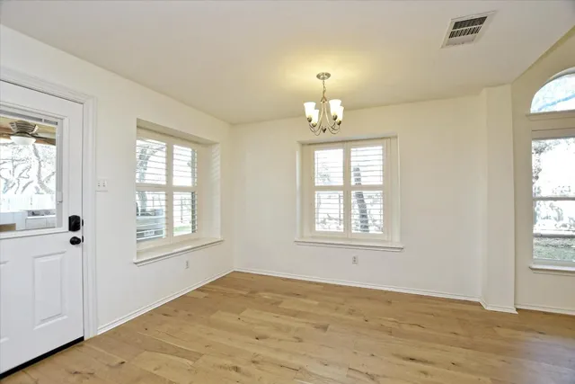 a view of an empty room with a window and wooden floor