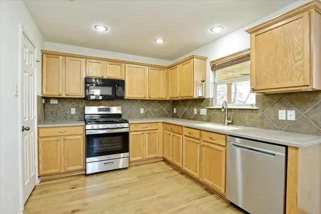 a kitchen with stainless steel appliances a sink cabinets and a window