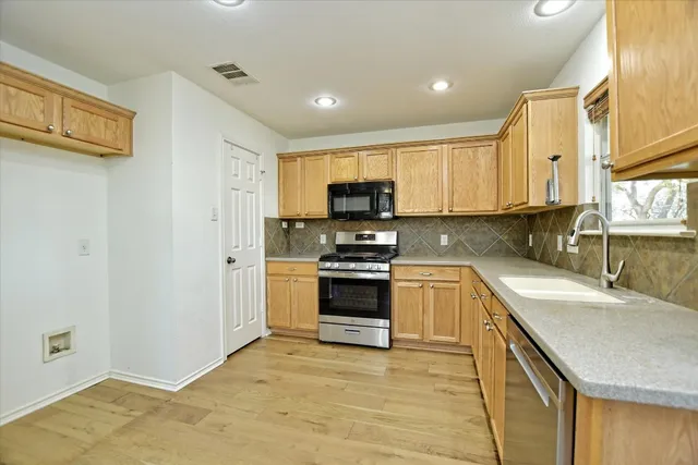 a kitchen with stainless steel appliances granite countertop a sink and a stove top oven