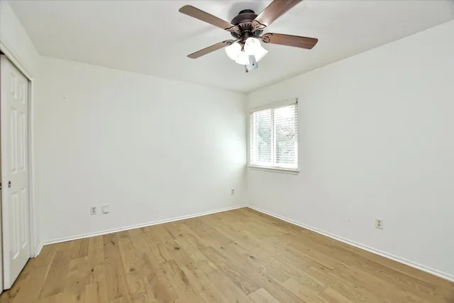 an empty room with a window and a fan