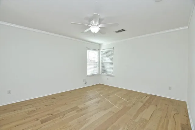 a view of a big room with wooden floor and chandelier fan