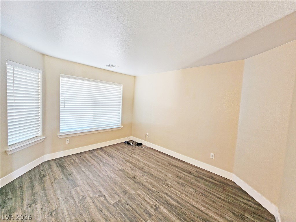 4591 Stoneham Street Pahrump, NV 89061 - Photo 7 of 42 Wood-look vinyl flooring extends through this neutral room, illuminated by multiple windows.