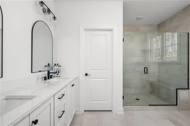 a bathroom with a granite countertop sink a mirror and shower