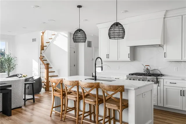 a kitchen with stainless steel appliances granite countertop a stove a sink a dining table chairs and cabinets