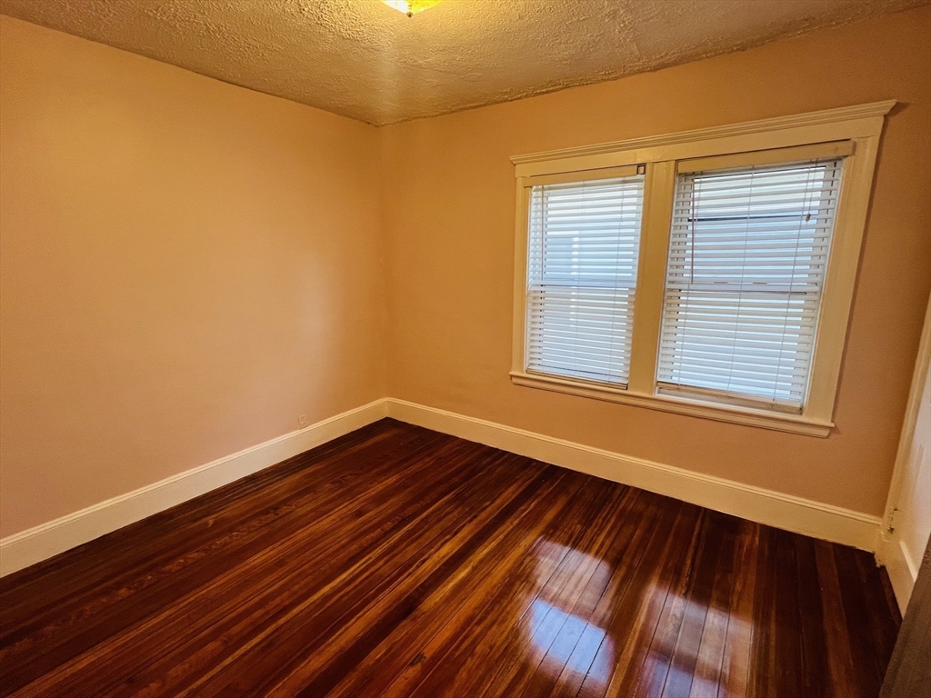 62 Westmore Road, Unit 2 Boston, MA 02126 - Photo 10 of 13 a view of an empty room with wooden floor and a window