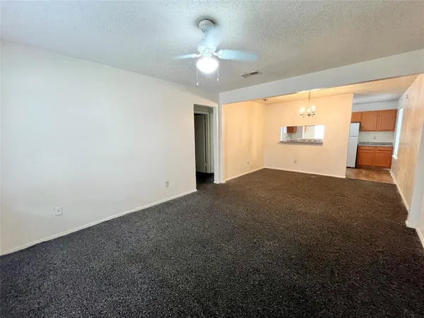 an empty room with windows and chandelier fan