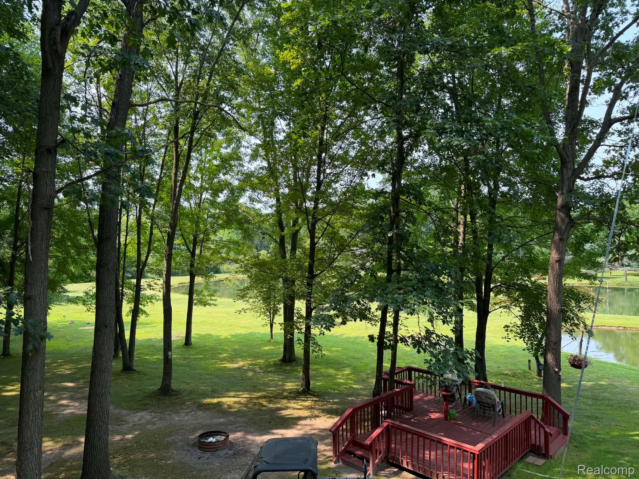 8110 North Latson Road Howell, MI 48855 - Photo 43 of 48 Mature wooded grounds featuring towering hardwood trees, expansive manicured lawn, and a custom composite deck with sturdy railings overlooking the property