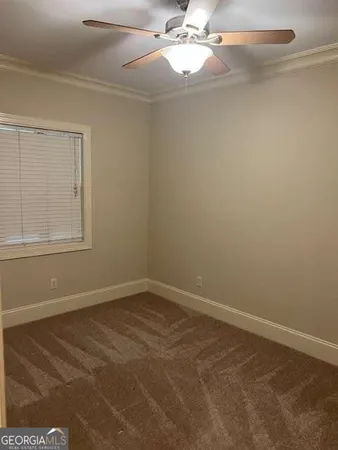 an empty room with a chandelier fan and windows