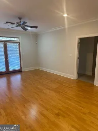 a view of an empty room with wooden floor and a window
