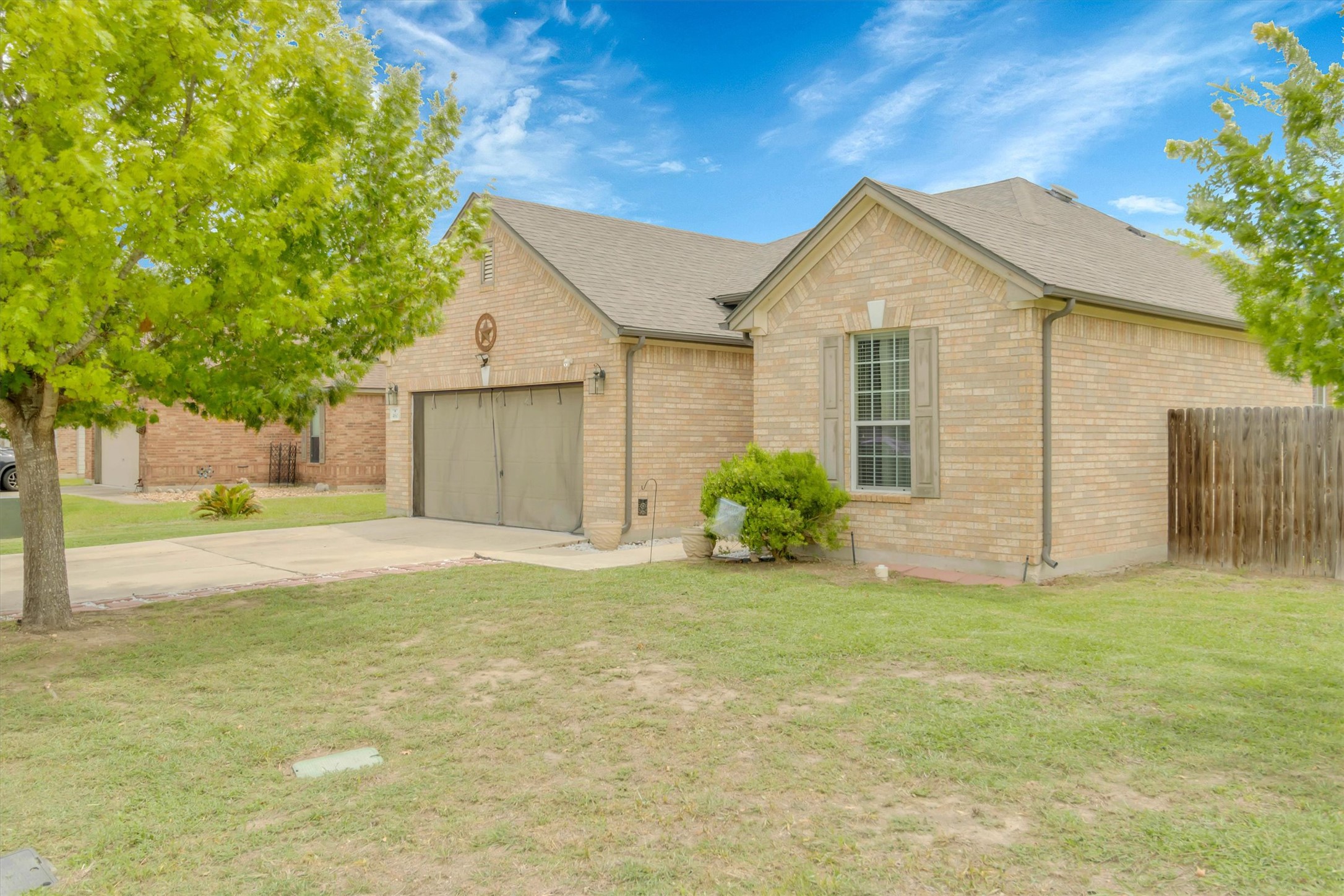 460 Waterleaf Boulevard Kyle, TX 78640 - Photo 3 of 30 A well-maintained brick exterior home boasts a garage and neatly kept lawn, framed by vibrant green trees.