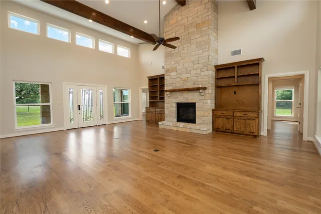 an empty room with wooden floor fireplace and windows
