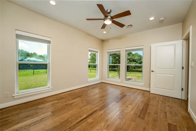 an empty room with wooden floor and windows