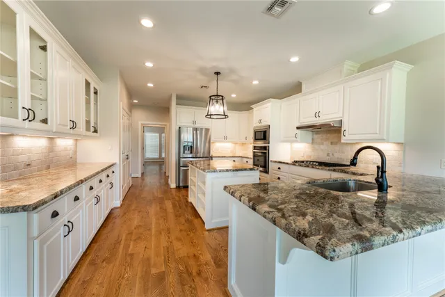 a large kitchen with stainless steel appliances granite countertop a lot of counter space and wooden floors