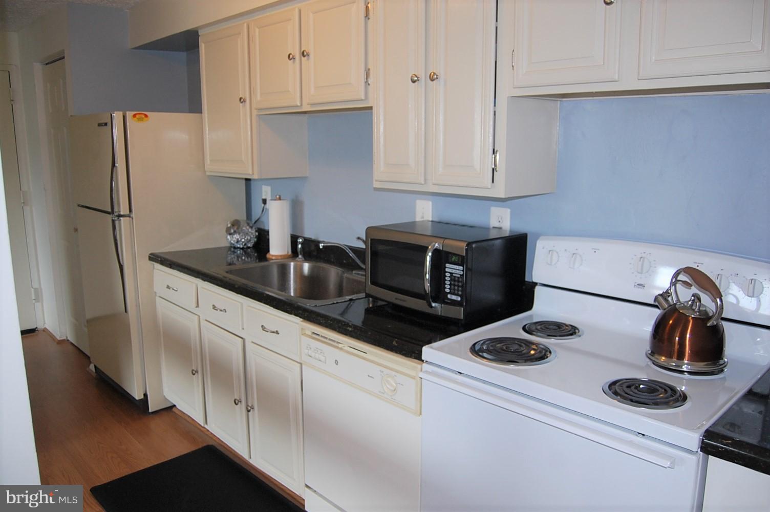 19501 Gunners Branch Road, Unit M Germantown, MD 20876 - Photo 6 of 11 a kitchen with refrigerator a stove a sink and cabinets